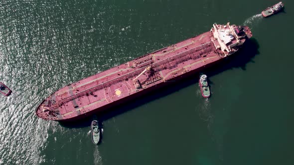 Aerial top down view of Tug boats assisting big oil tanker ship. alt