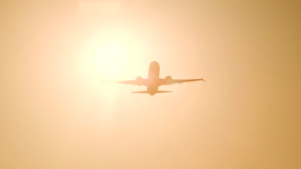 Take-off of a Passenger Plane From the Airport. Silhouette Against Background of Orange Sky Sunset. 