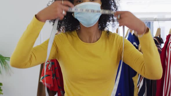 Portrait of female fashion designer wearing face mask with measuring tape around her neck alt