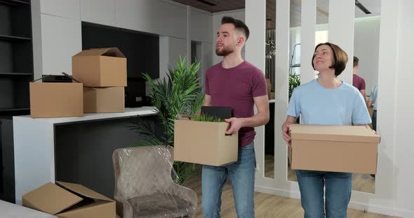 Happy Young Husband Lifting Excited Wife Celebrating Moving Day with Cardboard Boxes alt