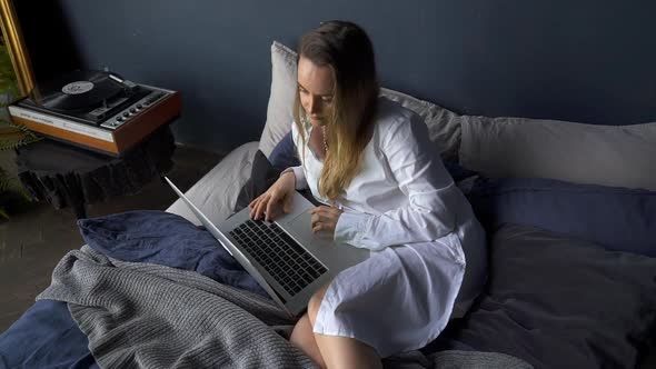 Woman Browsing Internet on Laptop and Sitting in Retro Stylish Bedroom Akspb alt