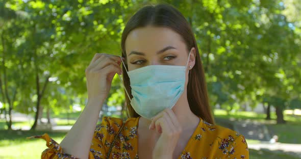 Portrait of a Young Woman Wearing Protective Mask in the Park. Concept of Health and Safety Life alt