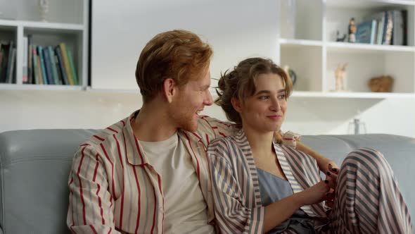 Married People Hugging Couch in Pajamas Closeup alt