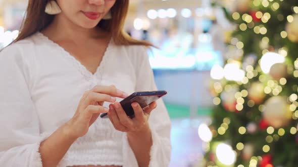 Young woman using phone at decorated stores and shopping mall