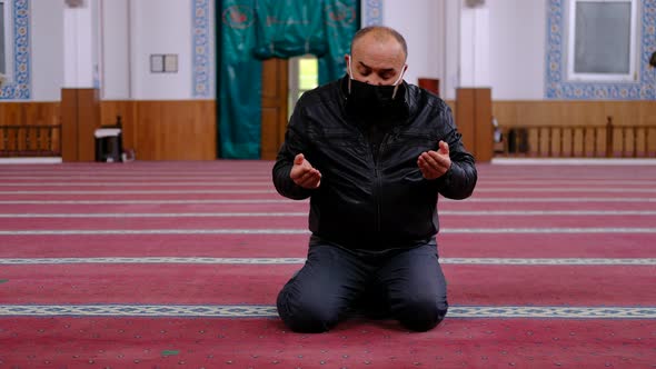 Masked man praying mosque alt