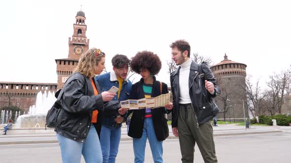 Slow motion four multiethnic friends traveller outdoor searching using tourist map alt