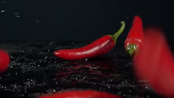 SLO MO Red Chilies Bouncing Off Water Covered Black Surface alt