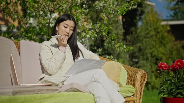Intelligent Beautiful Young Asian Woman Recording Voice Mail Sitting on Couch in Sunny Garden alt
