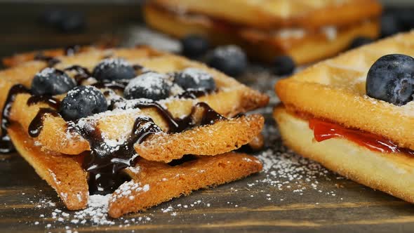 Belgian Waffles with Chocolate Sauce Jam and Blueberries in Powdered Sugar alt