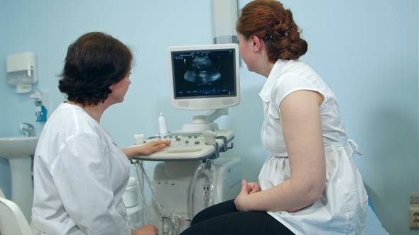 Female Doctor Showing Ultrasound Results to Woman Patient in Clinic