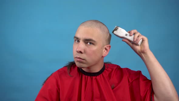 A Young Man Cuts Himself Baldly. A Man Uses a Hairdressing Machine Cuts His Hair. alt