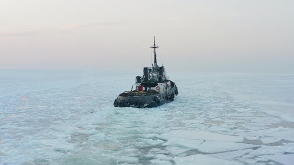 View of a Tug Making Its Way Through the Ice at Sunset alt