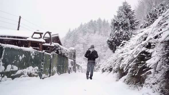 Anonymous man walking on snowy path alt