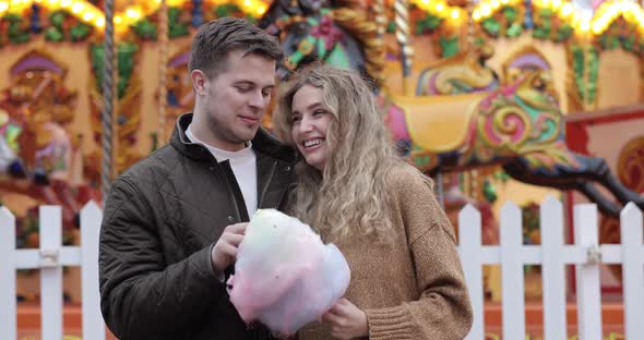 Happy couple at amusement park eating cotton candy