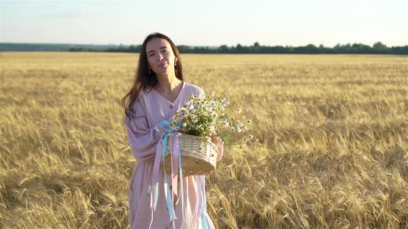 Back View of Girl in Wheat Field. Beautiful Woman in Dress with Ripe Wheat in Hands