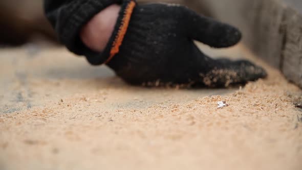 Man's Hand in Working Glove Crushes Sawdust From Table Into Chamber After Sawing Board with Circular alt