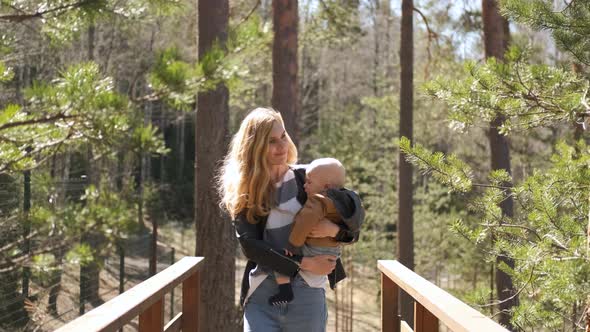 beautiful mother with a baby in her arms walks through the forest