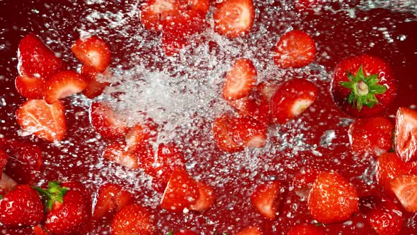 Super Slow Motion Shot of Flying Fresh Strawberries and Water Side Splash at 1000Fps. alt