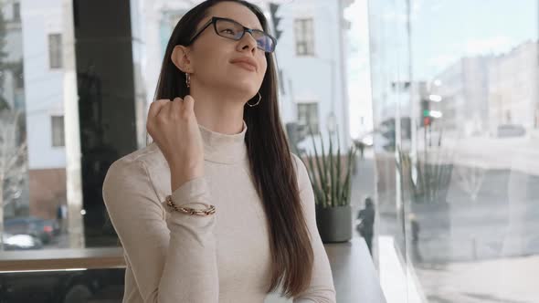 Young Woman Watching City Life Sitting Near the Big Window alt