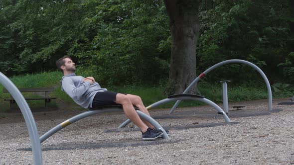 Athlete Using Outdoor Gym To Crunch Abs
