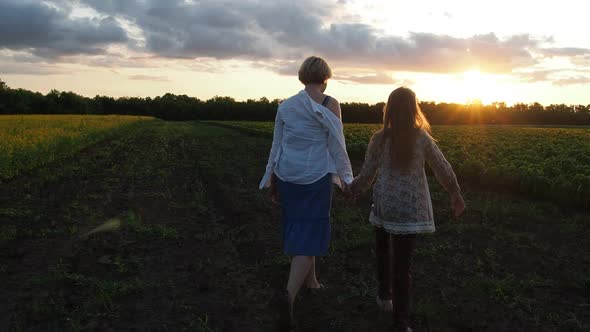 Mother and Daughter Walking Through the Plantation at Sunset