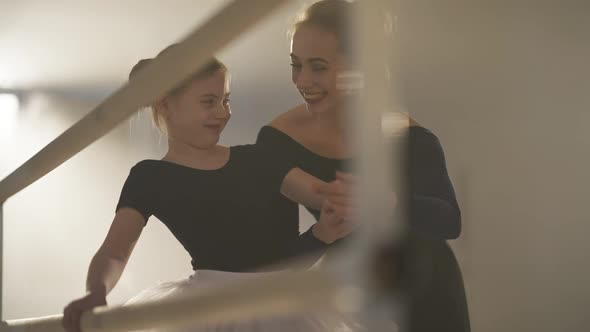 Gorgeous Slim Ballet Teacher Explaining Position to Cute Talented Girl in Ballet Studio alt