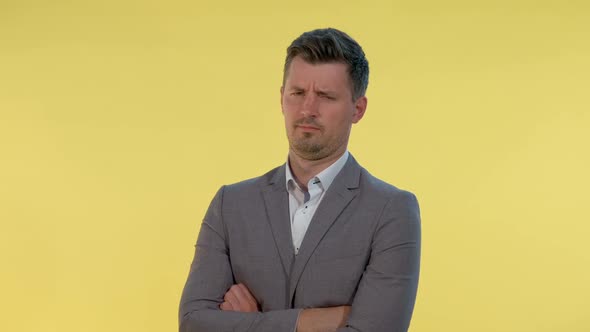 Close-up of Man in Suit Putting His Finger To the Temple on Yellow Background alt