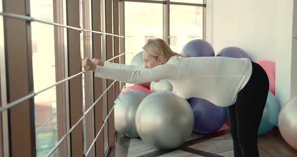 Pregnant Woman Exercising at Gym Near Window alt