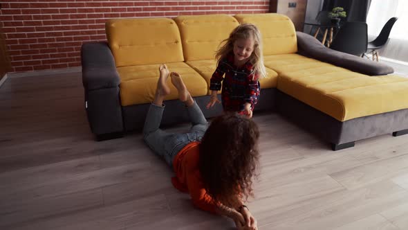 Little Girl Playing at Home with Mother and Climbing on Her Piggyback alt