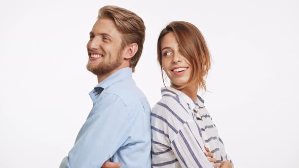Beautiful Caucasian Pair Standing Back to Back Flirtring Laughing on White Background alt