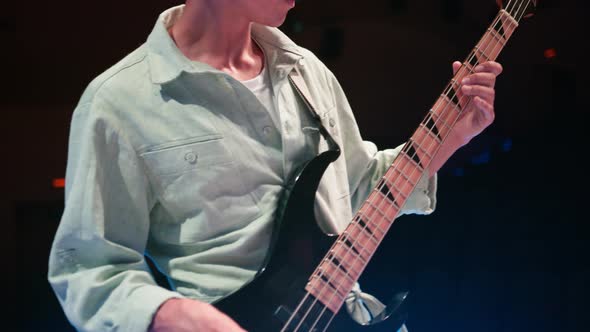 Bass Guitarist in Overalls Plays Black Bass Guitar at Concert