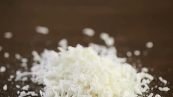 Dehydrated coconut flakes on a wood background alt