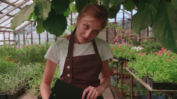 Female Gardener Checks Quality of Plants Takes Notes on Digital Tablet Walking Along Garden Center