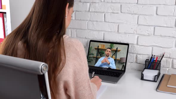 Woman student study online by conference video call laptop, writes in notebook alt