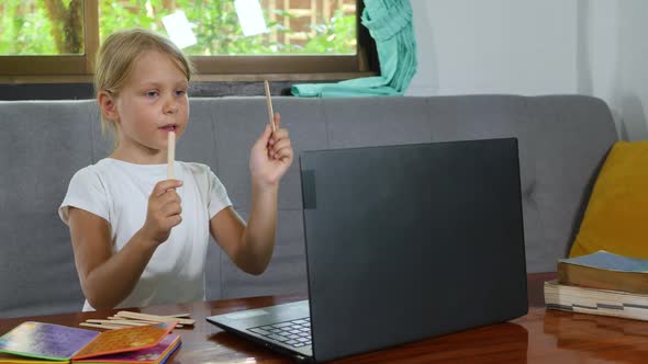 Cute Child Little Girl Counting Numbers and Does Math Homework Online at Home for Elementary School
