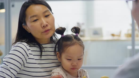 Asian Woman with Child Having Talk with Pediatrician alt