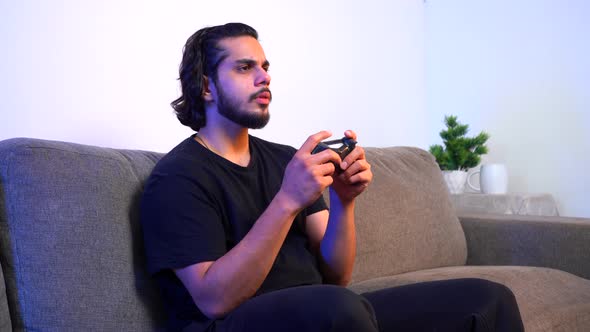 Indian gamer playing video games late at night alt