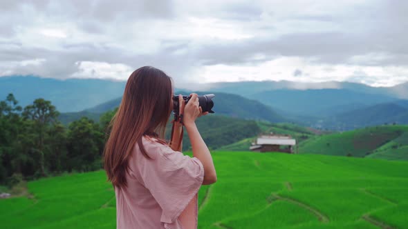 Young woman traveler on vacation taking a picture at beautiful green rice terraces