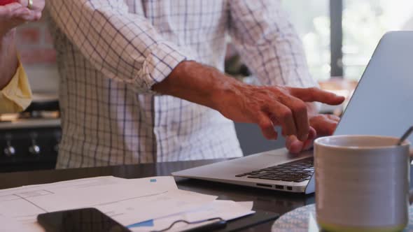 Senior Caucasian couple working together on a laptop at home alt