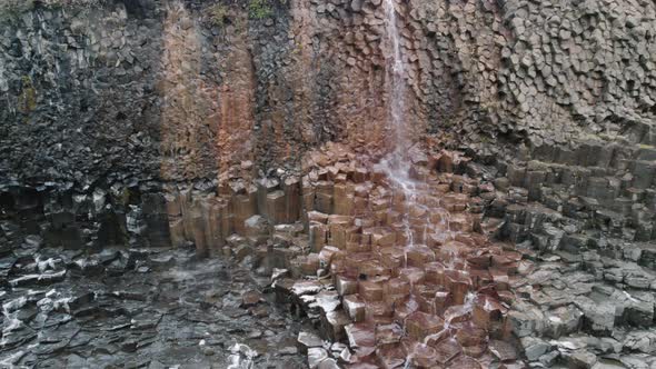 Trucking shot of waterfall flowing down basalt columns Studlagil Canyon, Iceland. alt