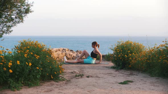 A Young Woman in Sportswear Exercising on Yoga Mat By the Sea alt