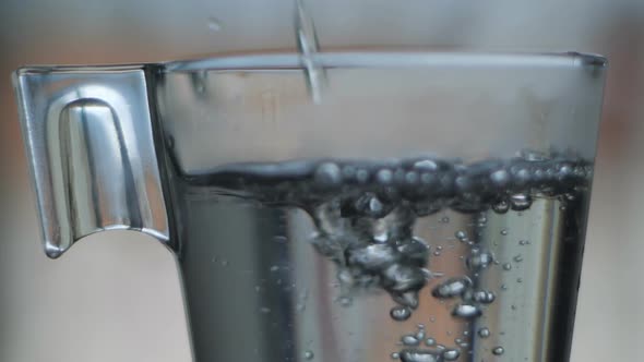 Hot water pouring in glass water slow motion