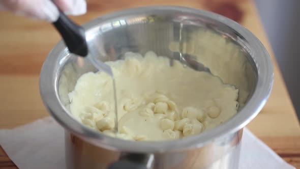 Сhef mixing melting white chocolate in a cup