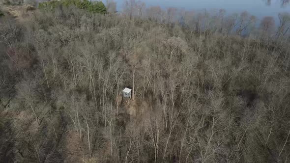 A rotating aerial 4K shot of an elevated wooden watchtower in a leafless forest in wisconsin