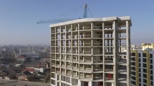 Aerial view of city residential area with high monolithic apartment building under construction alt