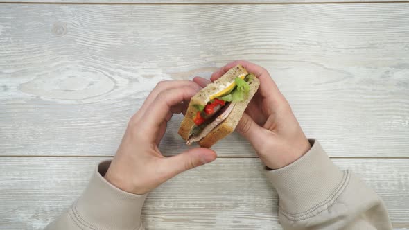 Human Hand Takes Sandwich From the Table and Eating. Synthetic Food. Take Out Food. Top View.
