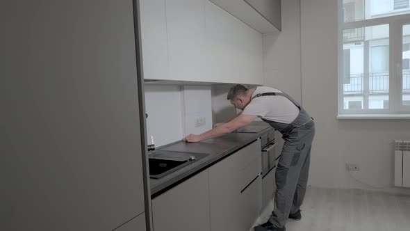 The Builder Checks the Dimensions and Quality of Installation of the Kitchen Furniture Structure alt