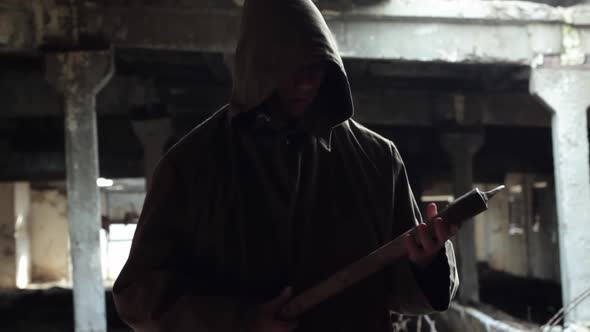a Man in a Dark Cloak with a Bloody Ax Walks in a Dark Abandoned Room alt