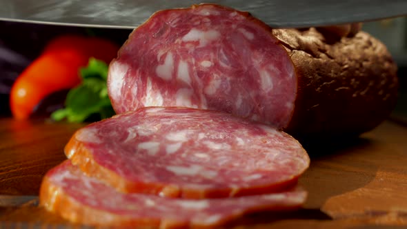 Cut Smoked Sausage with a Santoku Knife. Sausage Slices Lie on a Cutting Board Close-up. Cook the