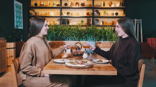 Beautiful Young Women Twins Dine in Restaurant. Sisters Are Looking at Camera alt